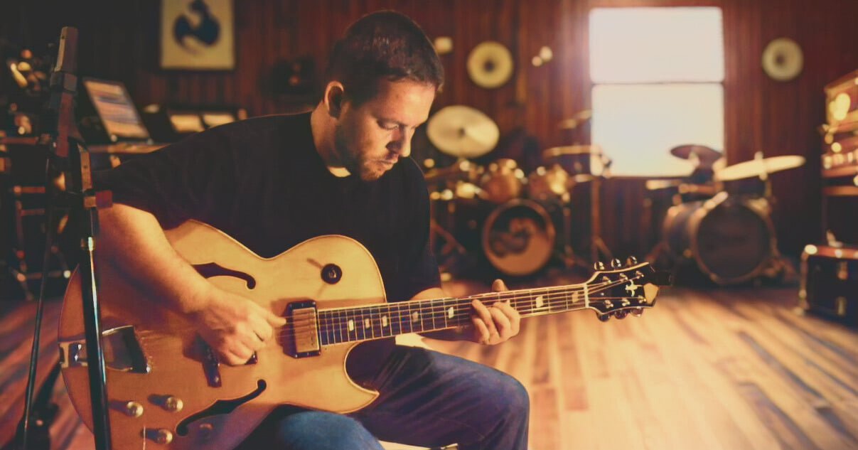 Denis Delphin tocando guitarra em estúdio