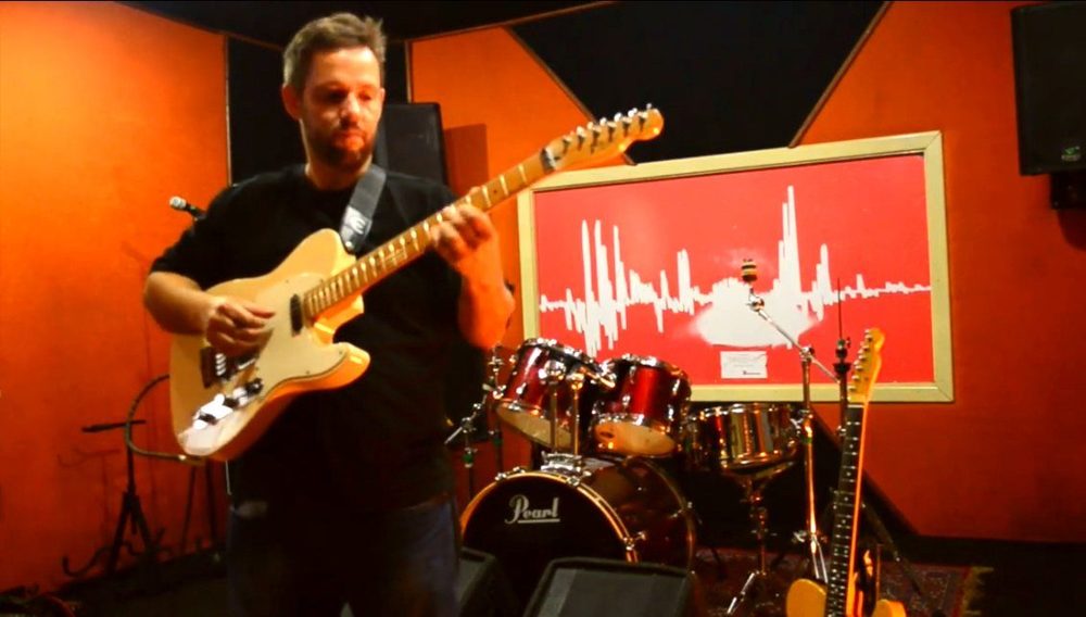 Denis Delphin tocando guitarra em estúdio