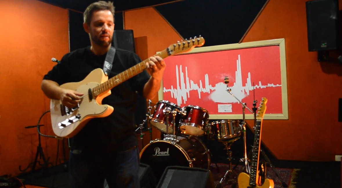 Denis Delphin tocando guitarra em estúdio de gravação